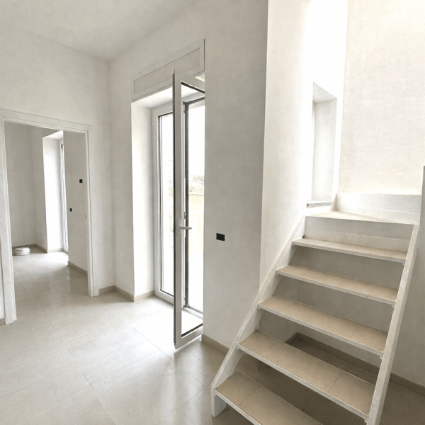 Interni attico moderno con scala minimalista, pavimenti color sabbia e infissi bianco optical - Progetto Arkigo