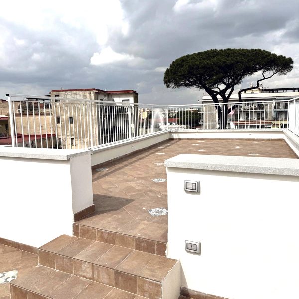 Ristrutturazione terrazzo mediterraneo con pavimentazione in gres porcellanato e vista sul pino secolare - Progetto Attico Vesuvio Arkigo